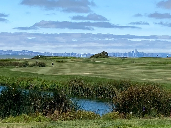 View of golf hole over small pond overlooking the bay